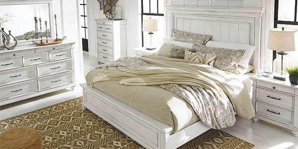 A white wood bed and coordinated bedroom furniture in a light-filled styled interior.