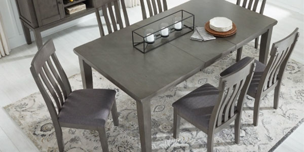 A rectangular dining table with upholstered wood chairs and a patterned area rug.