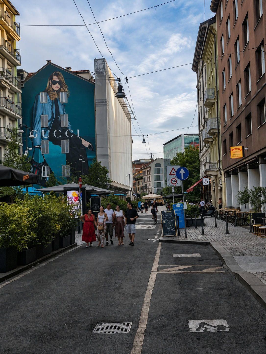 Pedestrian street in Milan facing a large Gucci fashion mural.