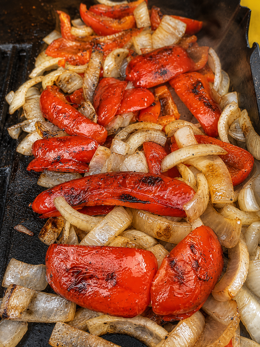 A cast-iron griddle of grilled peppers, onions, and squash