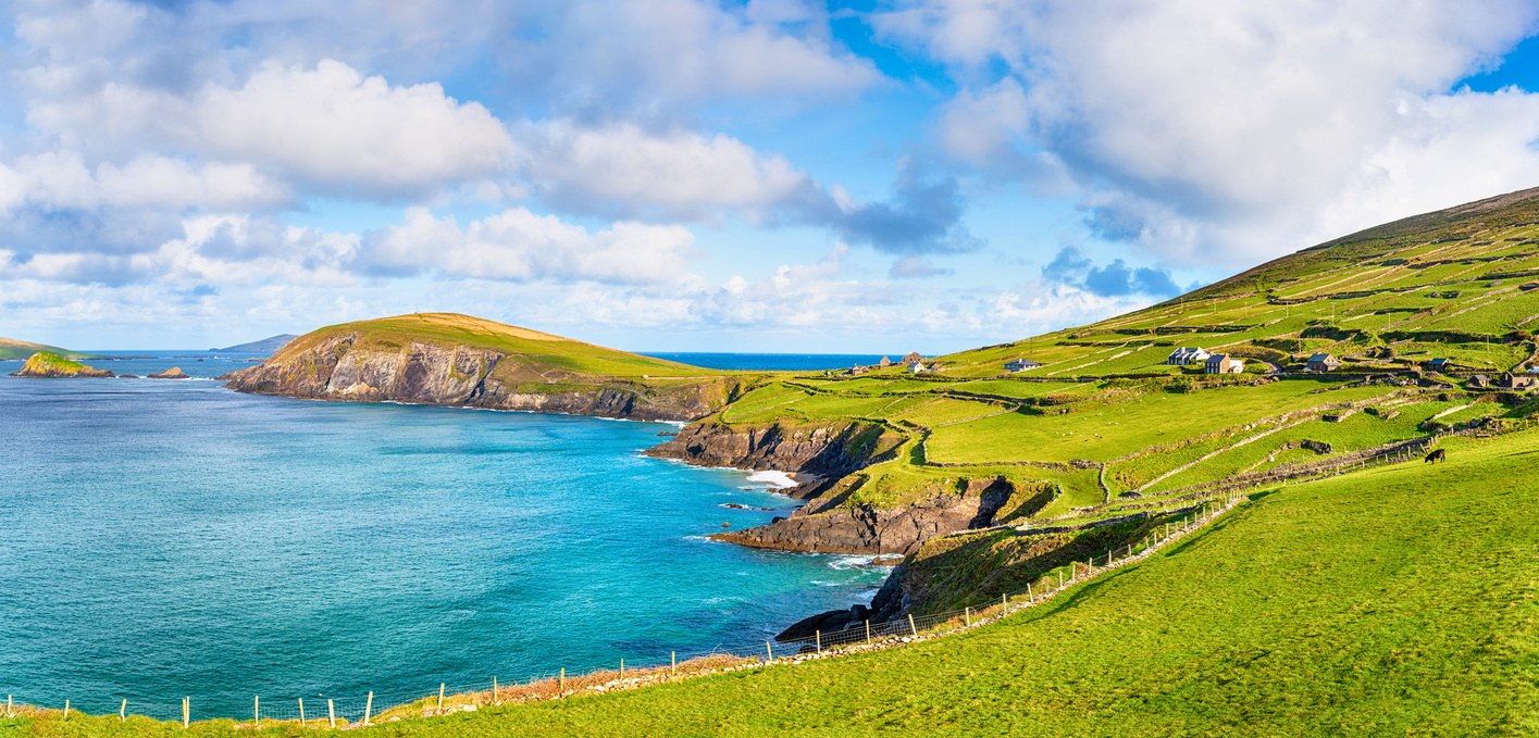 Green fields meeting turquoise water along Ireland's Atlantic coastline.