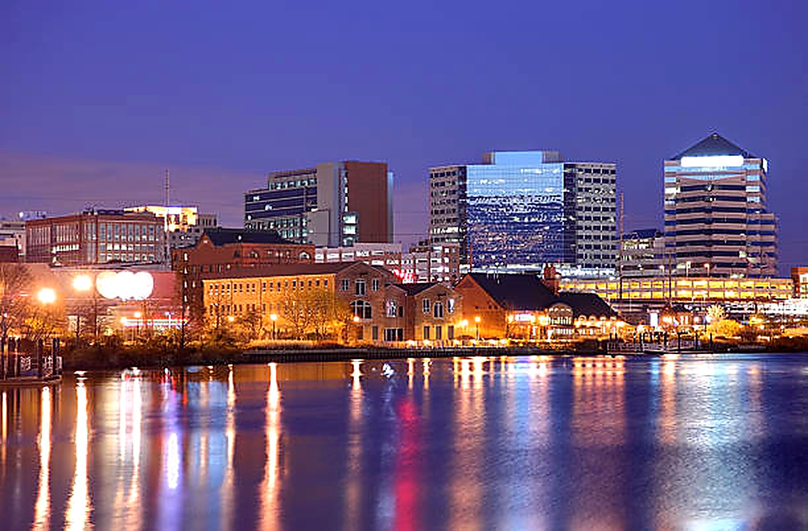 Wilmington riverfront skyline at dusk with lamplight reflecting on the Christina River