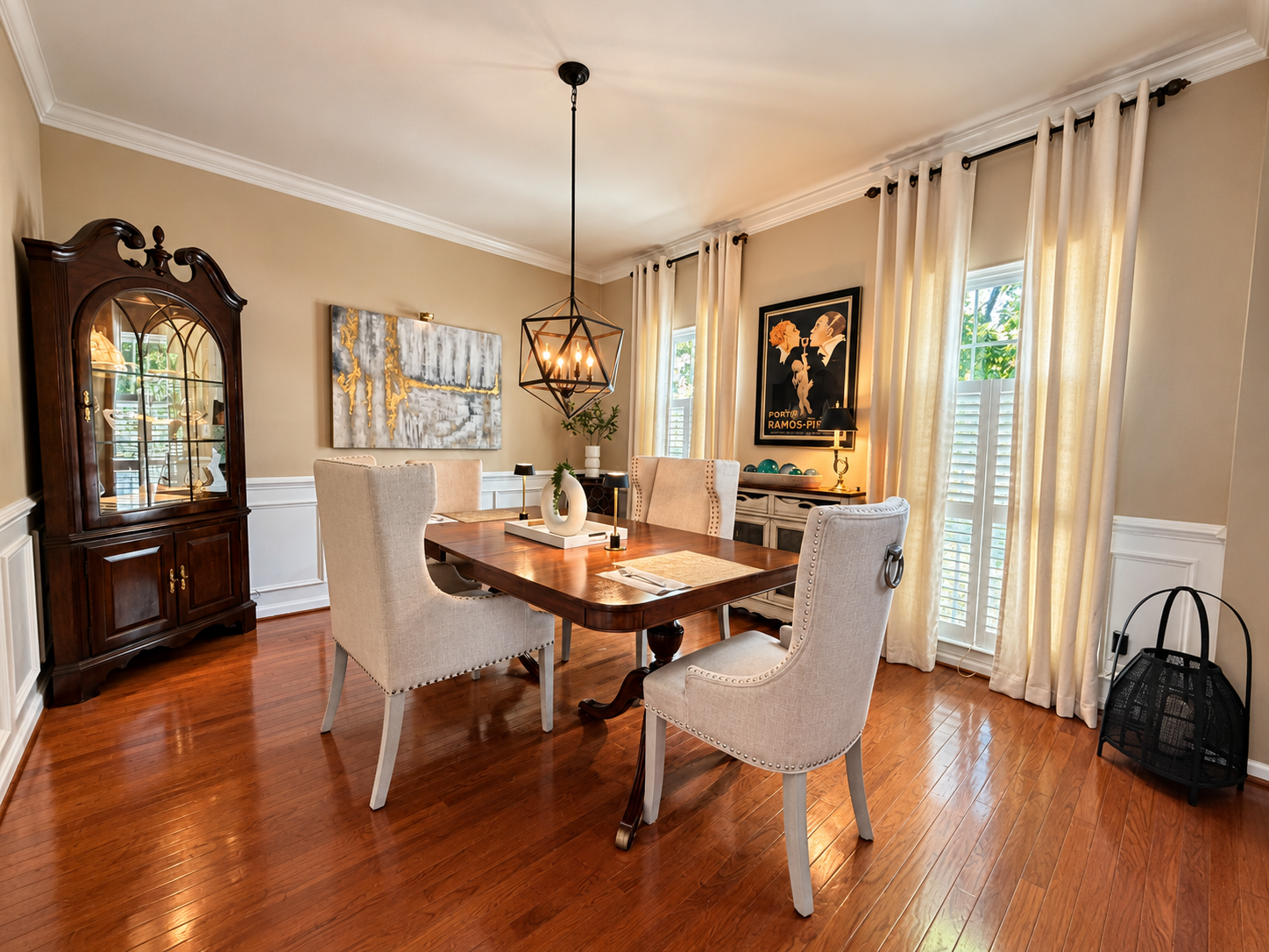 A wood dining table with upholstered chairs, a glass-front cabinet, framed art and floor-length curtains.
