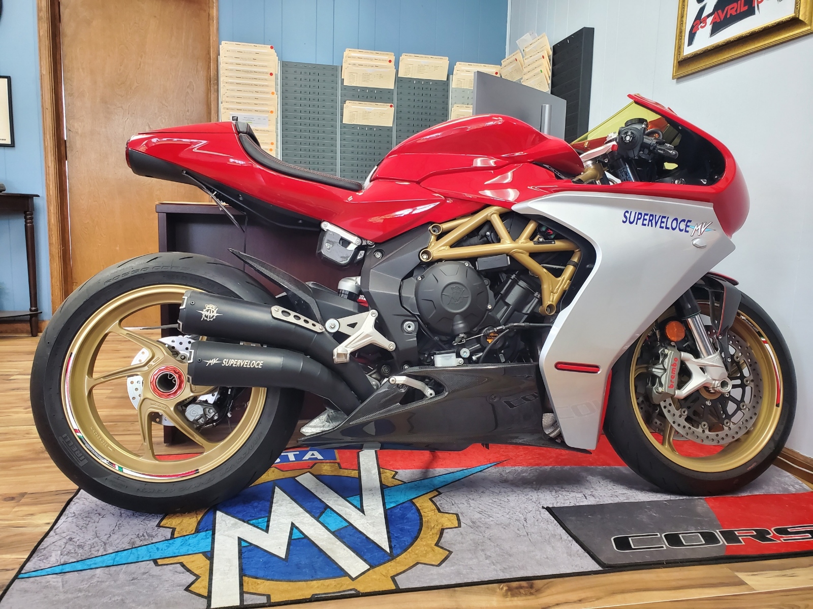 A red 2021 MV Agusta Superveloce parked on an MV Corse rug in the lobby of Edward J. Henry and Sons Auto Body