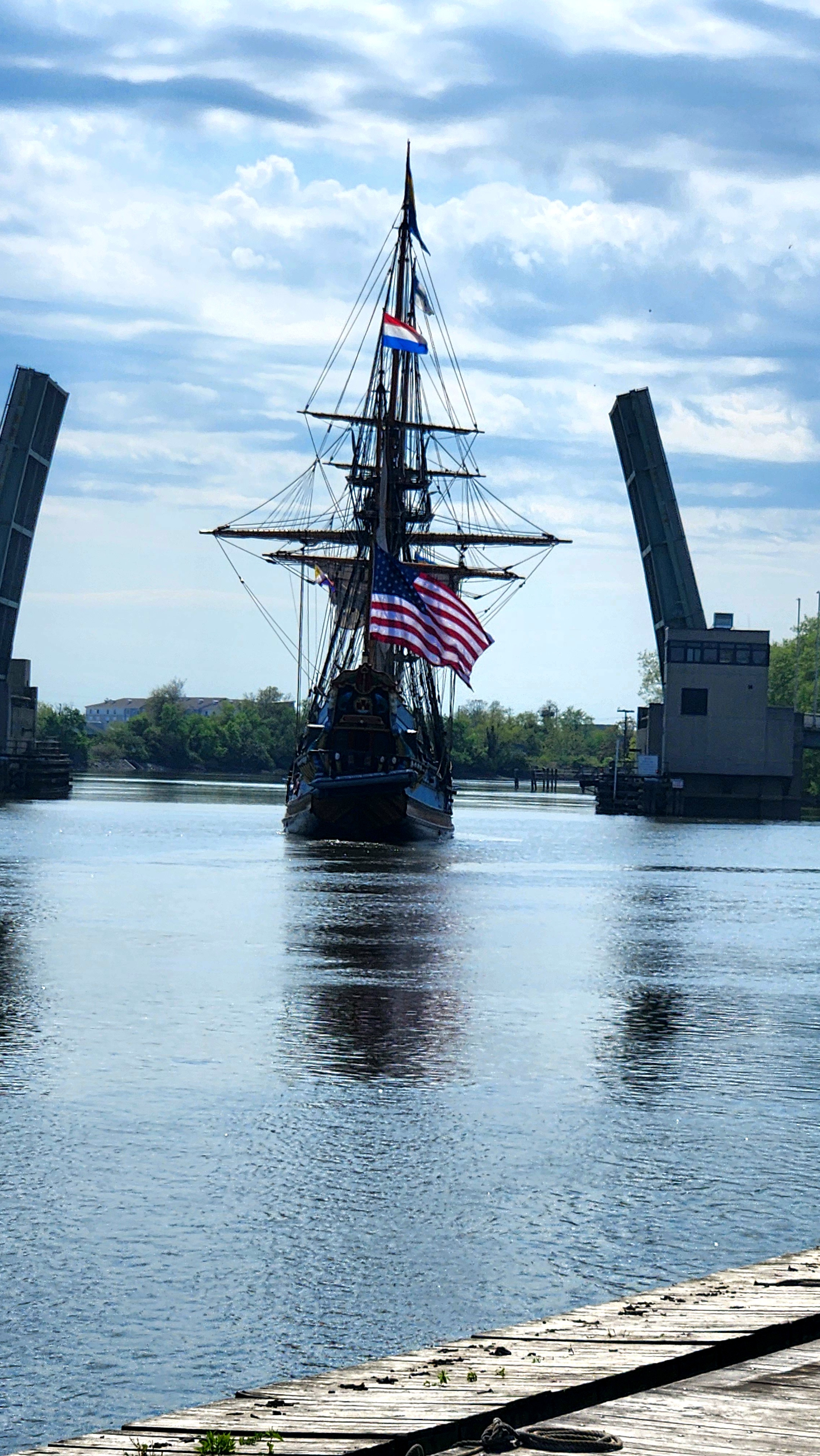 The Kalmar Nyckel sailing outbound between the open bridges of the Christina River