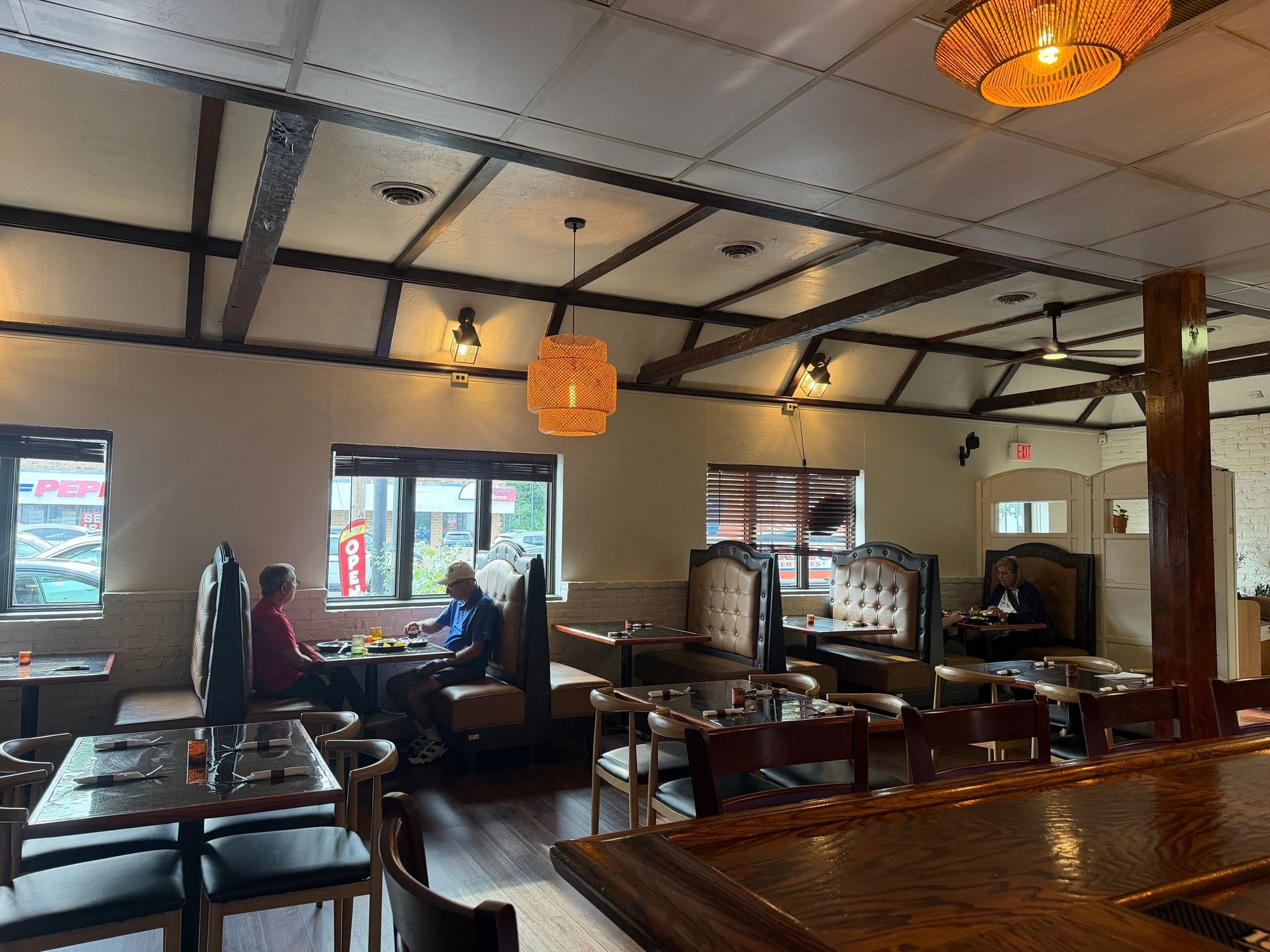 Guests dining at booths beside the street-facing windows inside MAIZ.