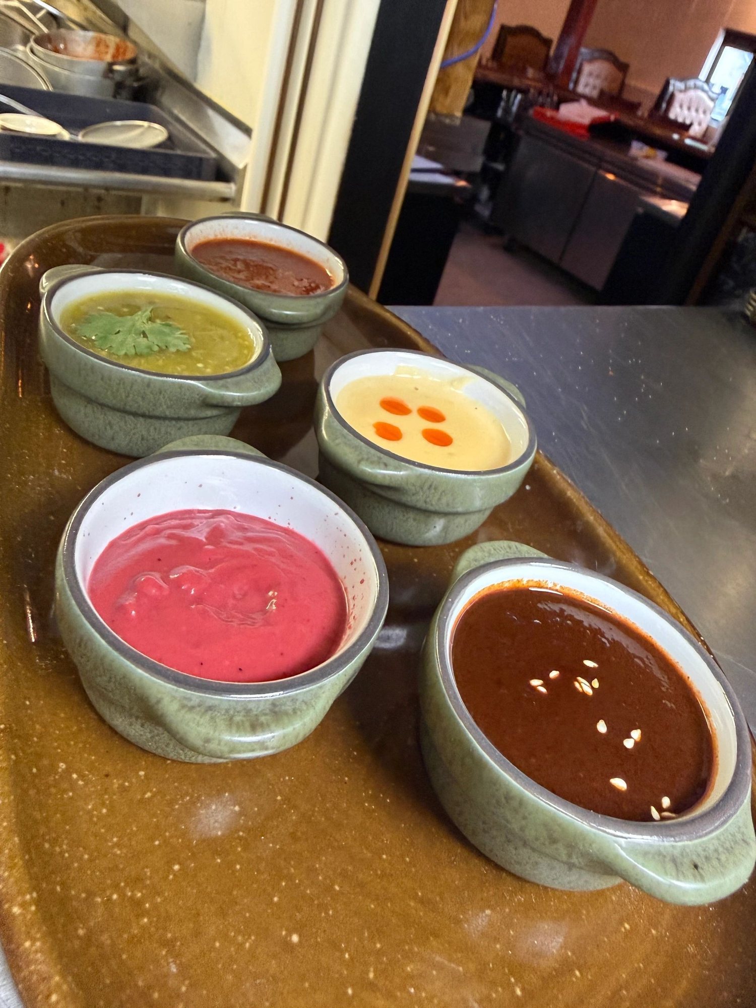 Five house-made sauces in small stoneware bowls on a tray at MAIZ.
